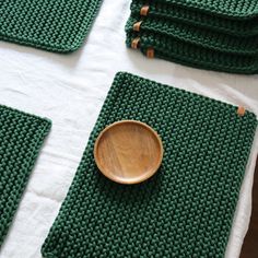 a wooden bowl sitting on top of a table next to green placemats and napkins