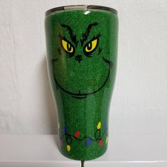 a green cup with yellow eyes and lights on it