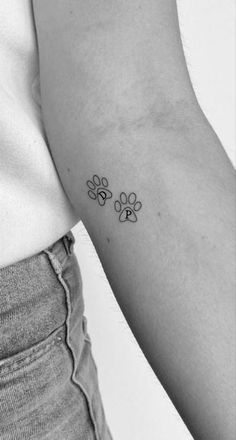 a woman's arm with a small paw tattoo on the left side of her arm