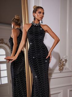 a woman standing in front of a mirror wearing a black dress with sequins