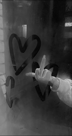 the hand is pointing at two heart shaped stickers on the glass window sill