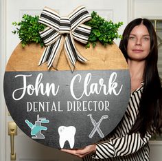 a woman holding a sign that says john clark dental director