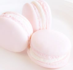 three pink macaroons sitting on top of a white plate next to each other