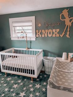 a baby's room with green walls and white crib in the corner, stars on the floor