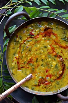 a large pan filled with green food on top of a table next to some leaves