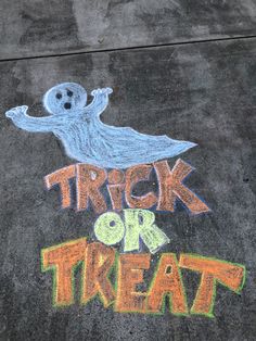 chalk drawing on sidewalk with trick or treat written in orange and green marker next to ghost