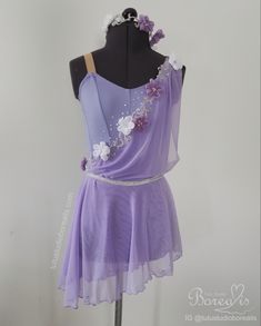 a dress on a mannequin with flowers and pearls around the neck, in purple