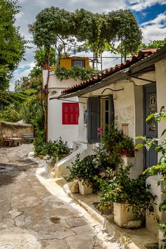 an old house with potted plants on the outside and red shutters in front