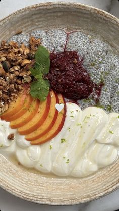 a bowl filled with fruit, yogurt and granola on top of a table