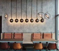 a long table with chairs and lights hanging from the wall above it in a restaurant