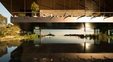 people are sitting on the roof of a building overlooking a body of water and trees