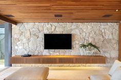 a large flat screen tv mounted to the side of a stone wall