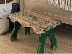 an old wooden bench sitting on top of a hard wood floor next to a pillow