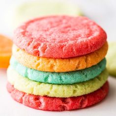 a stack of colorful cookies sitting on top of each other next to an orange slice