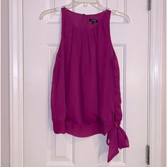 Sleeveless Blouse With Pleading Around Neckline Has Band At The Bottom And Ties In A Bow. The Back Is Keyhole With A Button Closure, Size Small, New With Tags Has An Extra Button Chic Purple Tank Top For Spring, Purple Tank Camisole For Spring, Purple Casual Tank Top For Party, Elegant Purple Camisole For Summer, Purple Camisole Top For Spring, Casual Purple Tank Top For Party, Purple Tank Top For Spring, Purple Sleeveless Tops, Purple Halter Neck Top For Summer