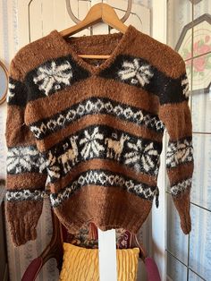 This super soft sweater was made by hand from a wool blend in medium brown and black, accented by various designs in light beige. The measurements, taken with the sweater lying flat, are: shoulder to shoulder, 18 inches; armpit to armpit, 20 inches; sleeves, 22 inches; length, 20 inches; bottom edge, 13 inches (with stretchy ribbing). In very good condition. Brown Knit V-neck Sweater For Winter, Cozy Knitted Brown Sweater, Brown Knitted V-neck Sweater, Cozy Brown Knit V-neck Sweater, Brown Nordic Sweater For Fall, Brown Fair Isle Sweater For Fall, Vintage Brown Sweater With Fair Isle Pattern, Nordic Brown Knit Sweater, Brown Nordic Knit Sweater