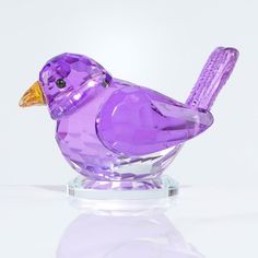 a purple glass bird sitting on top of a table