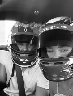 two people wearing helmets sitting in a car