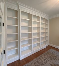 an empty room with white bookcases in it