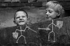 two young boys standing next to each other with chalk drawings on them