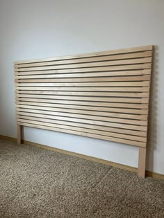 a wooden slatted headboard against a wall in a room with carpeting