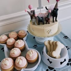 a table topped with cupcakes and cakes covered in frosting next to a cake