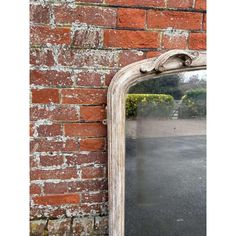 an old mirror is leaning against a brick wall