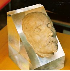 a sculpture of a man's head is shown on a metal block that sits on a wooden table