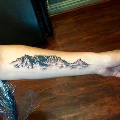 a person with a mountain tattoo on their arm