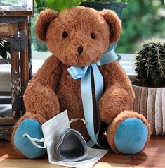 a brown teddy bear sitting on top of a table next to a potted plant