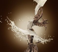 an artistic photograph of milk being poured into a glass with liquid pouring out of it