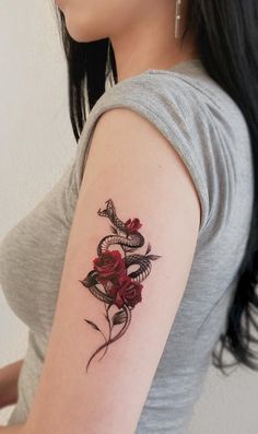 a woman with a tattoo on her arm holding a red rose and a snake wrapped around it