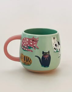 a ceramic mug with cats painted on the outside and inside, sitting on a white surface