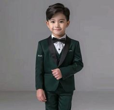 a young boy wearing a green suit and bow tie