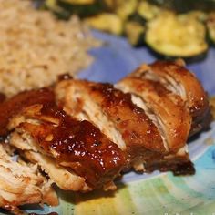 some meat and rice on a plate with broccoli in the backgroud