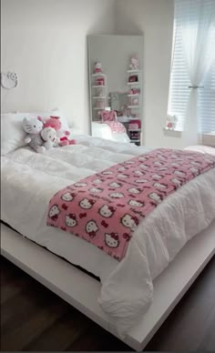 a white bed topped with two pink and white bedspreads covered in hello kitty blankets