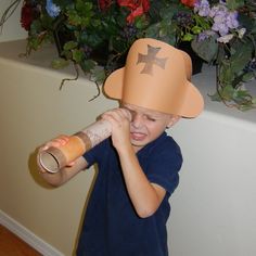 a young boy wearing a paper hat and holding a bottle