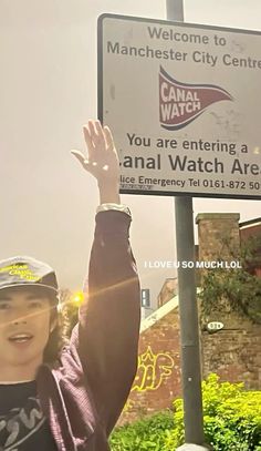 a woman holding up her hand in front of a sign