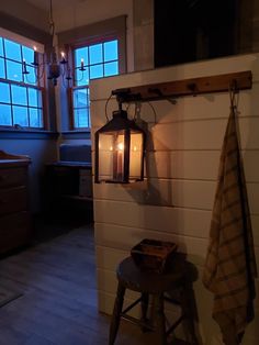 a lantern hanging from the side of a wall next to a stool with a towel on it