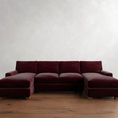 a red couch sitting on top of a hard wood floor next to a white wall