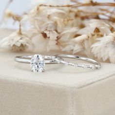 a white gold engagement ring set with a round brilliant cut diamond in the center, on top of some dried flowers