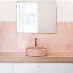 a bathroom with pink and gold accents on the wall, sink and mirror above it