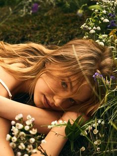 a woman laying in the grass with flowers around her