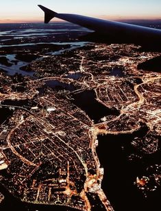 an aerial view of the city lights and water at night, taken from an airplane