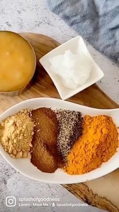 various spices are arranged in white bowls on a wooden tray next to a bowl of yogurt