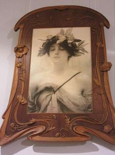 an ornate wooden frame with a woman's face in the center and flowers on her head