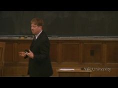 a man standing in front of a blackboard giving a lecture