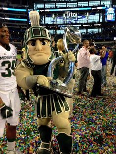 a football player holding a trophy in the middle of confetti