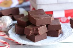 chocolate fudges stacked on a plate with candy canes in the foreground