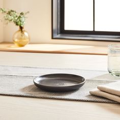 a table with a bowl, glass and napkins on it